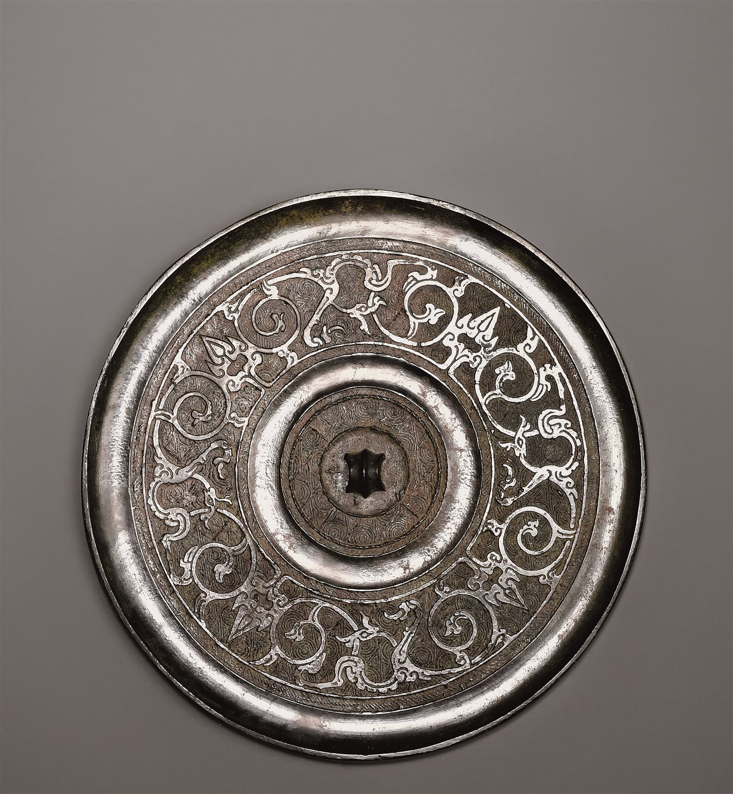 全镜以圆涡纹为地纹,主题纹饰为四组蟠螭纹缠绕盘曲组成,蟠龙纹之间